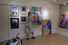 Rob de Koter hanging the paintings and his photographs